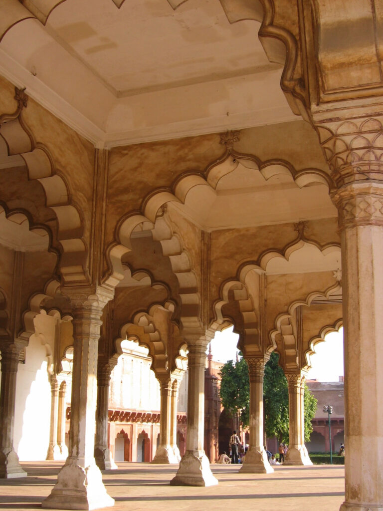 Galerie majestueuse aux arches infinies baignée de lumière dorée, où le temps semble ralentir à l’ombre des pierres sculptées