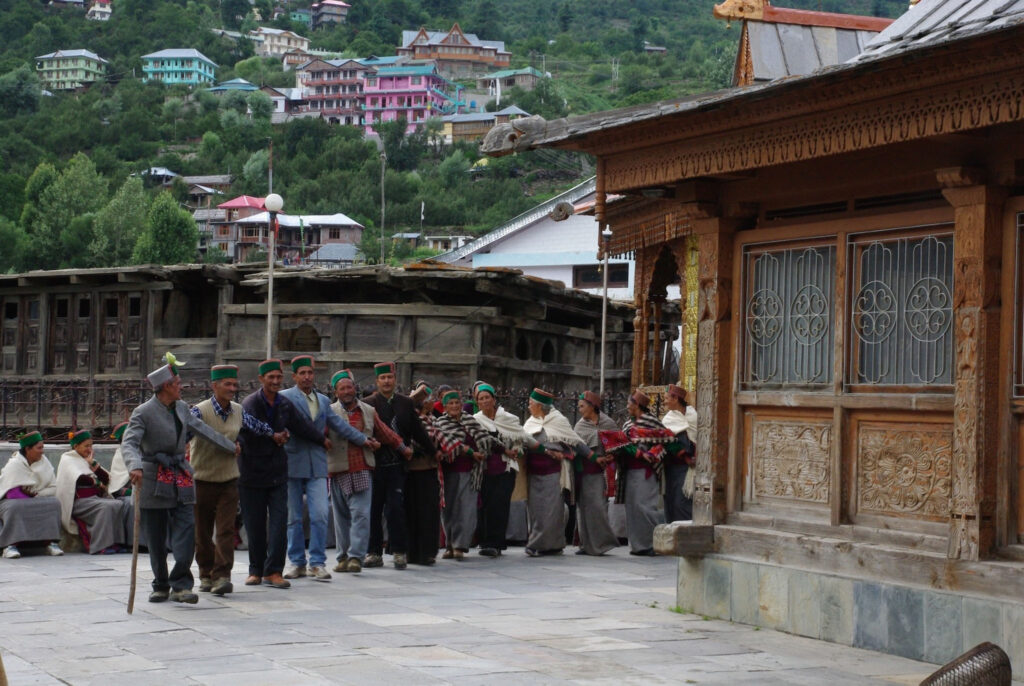 Danse collective traditionnelle devant un temple en bois, au cœur d’un village de montagne coloré (?)
