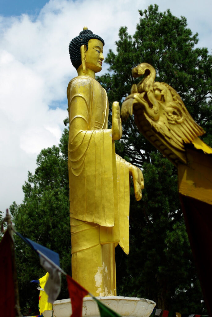 Statue de Bouddha dorée entourée de drapeaux de prière