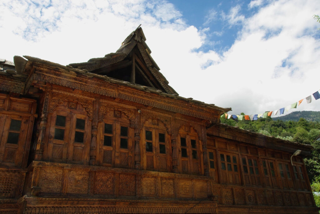 Façade en bois finement sculptée d’un bâtiment traditionnel de montagne avec drapeaux de prière