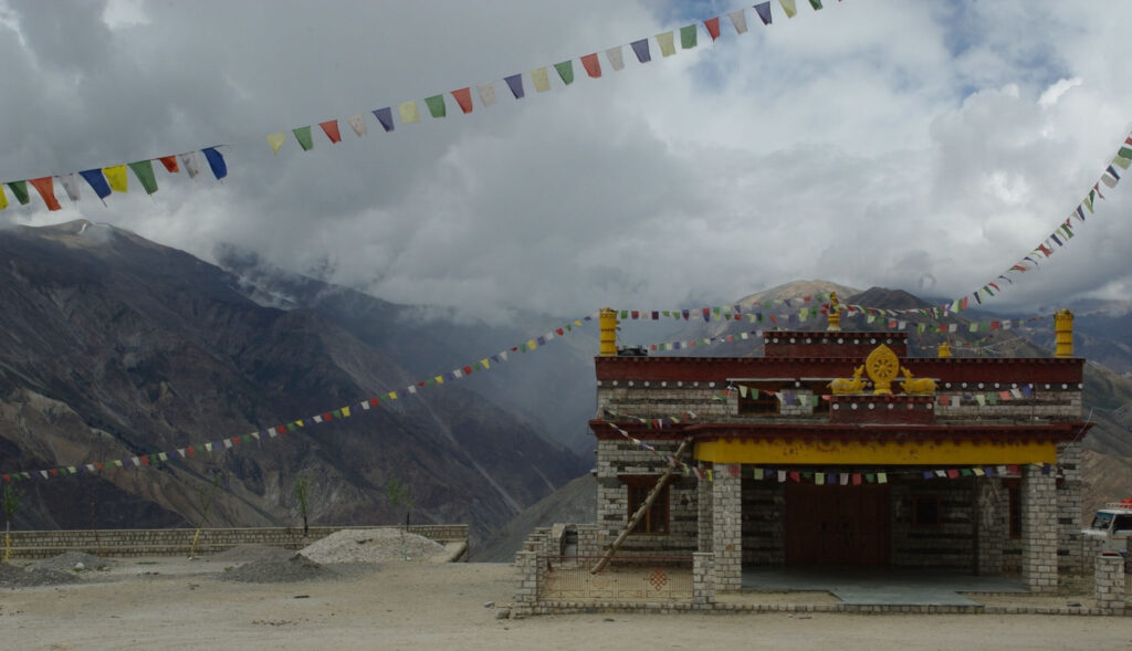 Temple de montagne orné de drapeaux de prière sous un ciel nuageux (?)