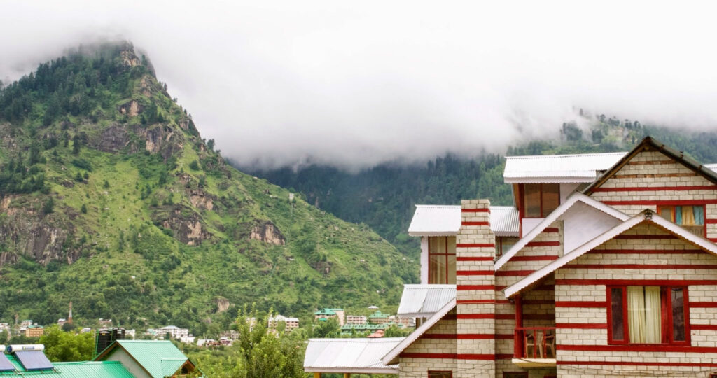 Maisons paisibles nichées au pied des montagnes embrumées, où la nature semble doucement envelopper le quotidien (?)