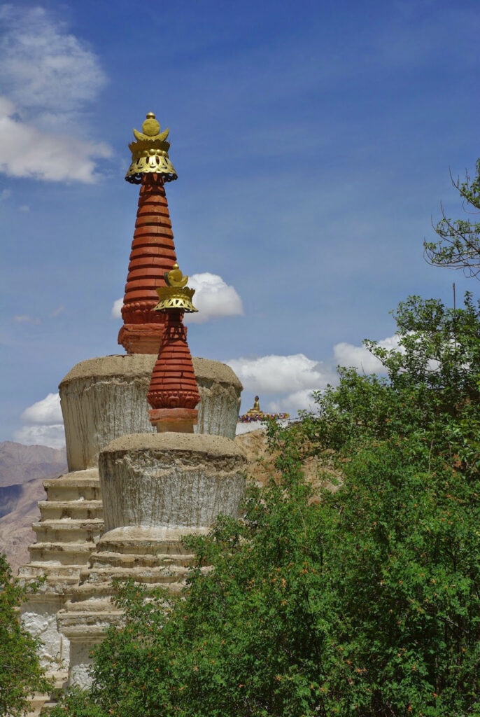 Stupas élancés aux ornements dorés émergeant d’une végétation verdoyante sous un ciel limpide et lumineux (?)